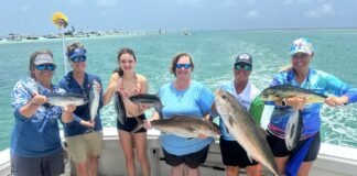 a group of people on a boat holding fish