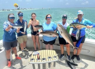 a group of people on a boat holding fish