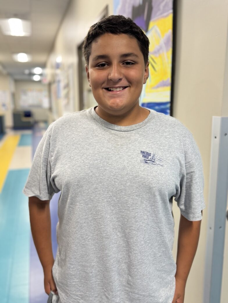 a boy standing in a hallway with his hands in his pockets