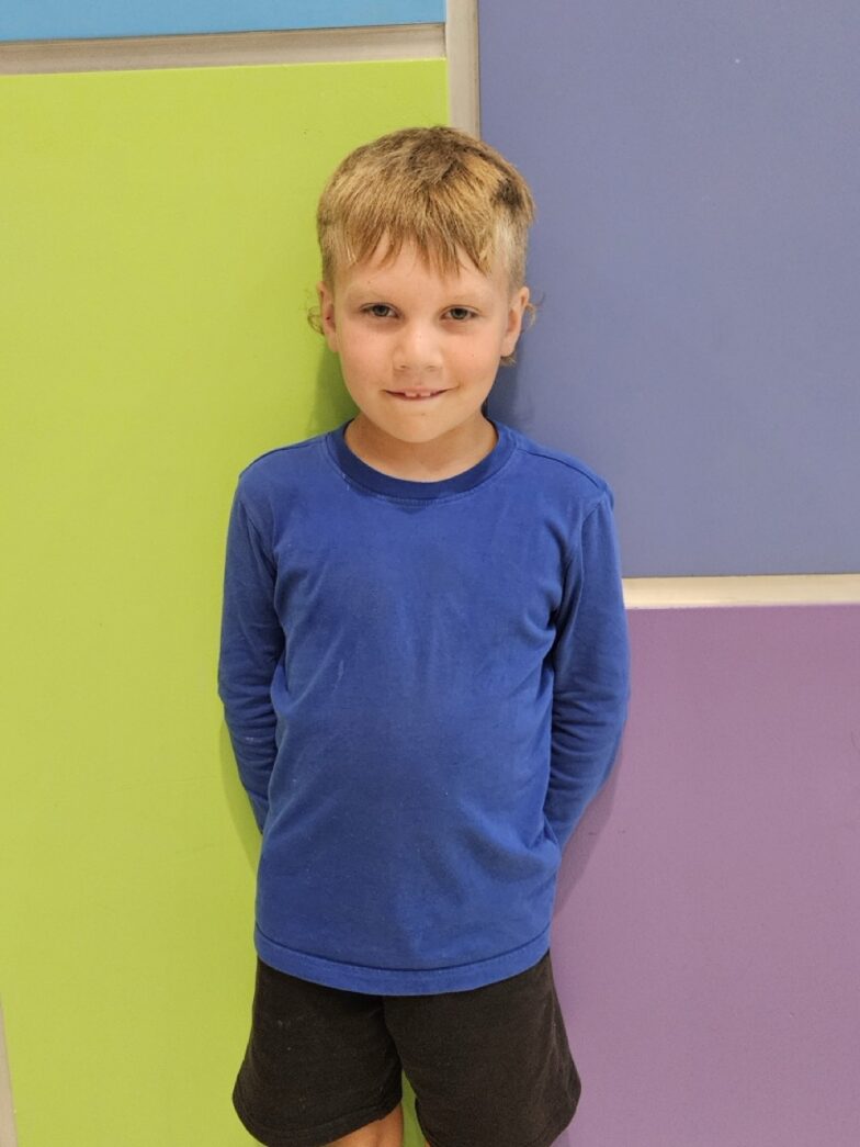 a young boy leaning against a colorful wall