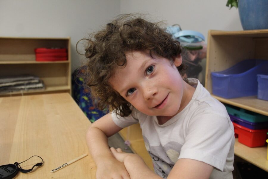 a young boy sitting at a table with a remote control