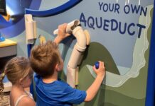 a boy and a girl painting a sign on a wall