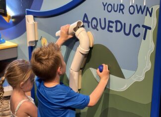 a boy and a girl painting a sign on a wall