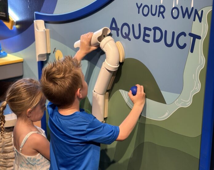 a boy and a girl painting a sign on a wall