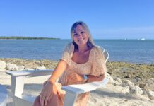 a woman sitting on a white chair on the beach