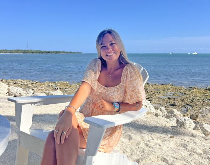 a woman sitting on a white chair on the beach
