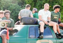 a group of young men sitting on top of a green truck