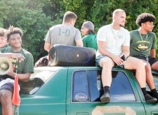 a group of young men sitting on top of a green truck