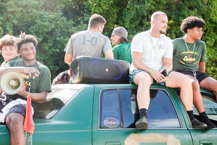 IMG_2452 Large a group of young men sitting on top of a green truck