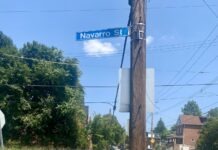a woman standing on the side of a road next to a street sign