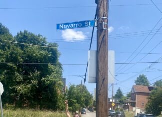 a woman standing on the side of a road next to a street sign