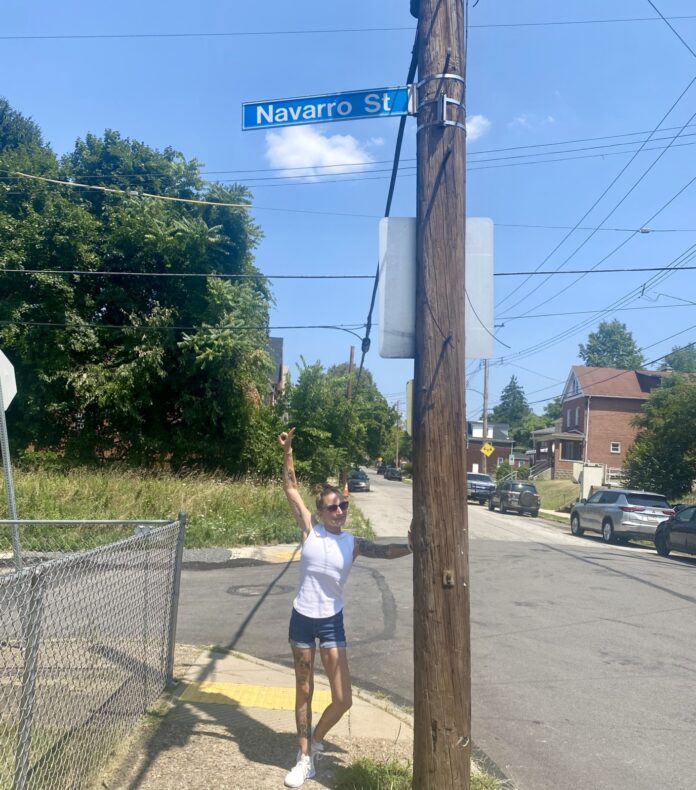 a woman standing on the side of a road next to a street sign