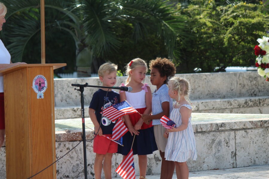 a woman standing at a podium speaking to children