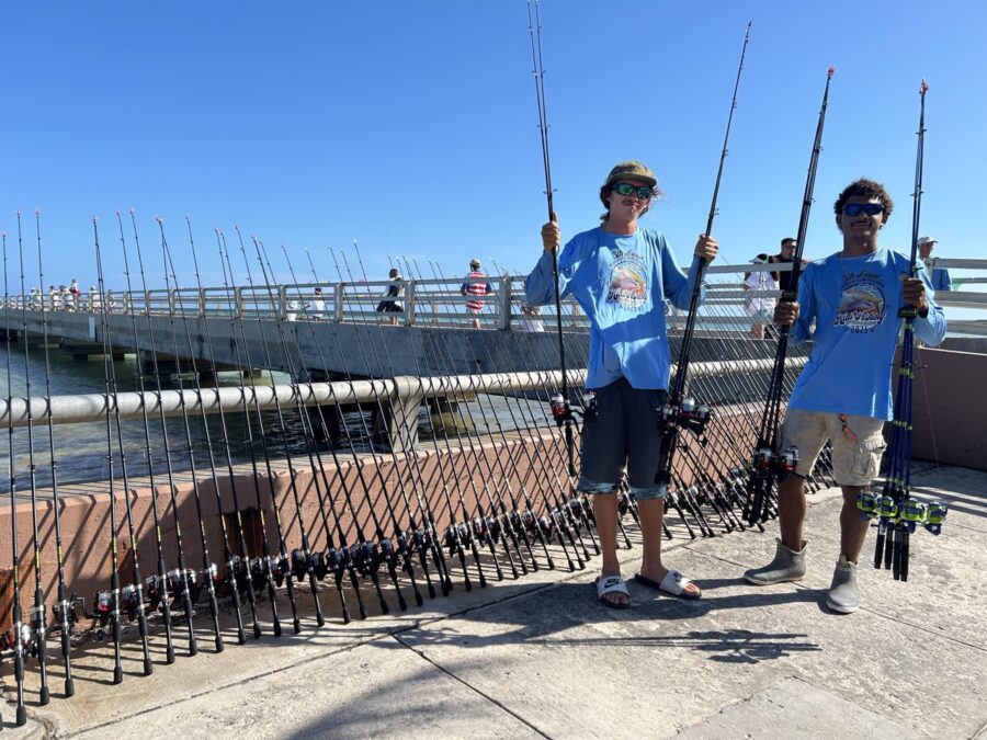 two boys holding fishing rods on a pier