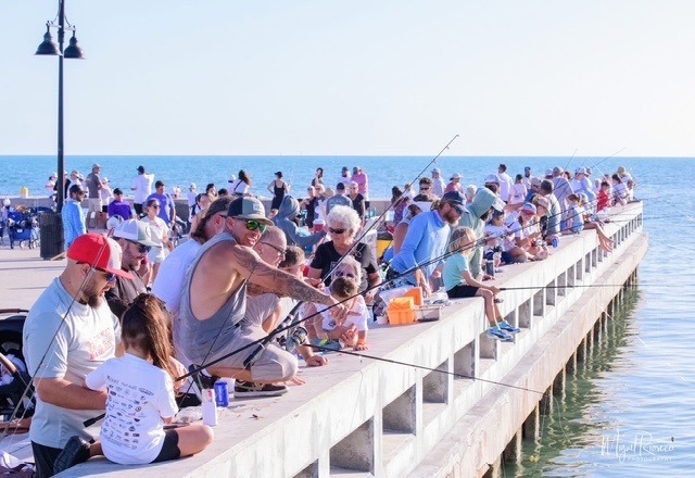a group of people sitting on a pier fishing