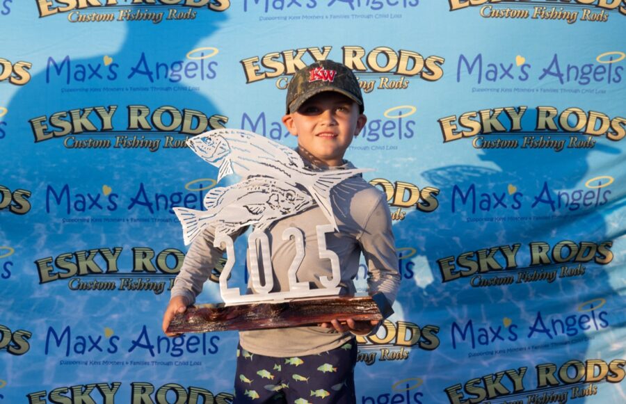 a young boy holding a trophy in front of a backdrop