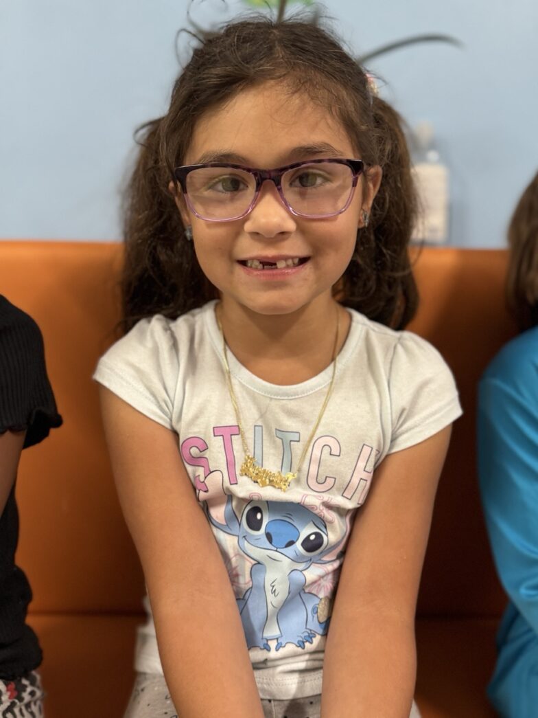 a little girl with glasses sitting on a couch