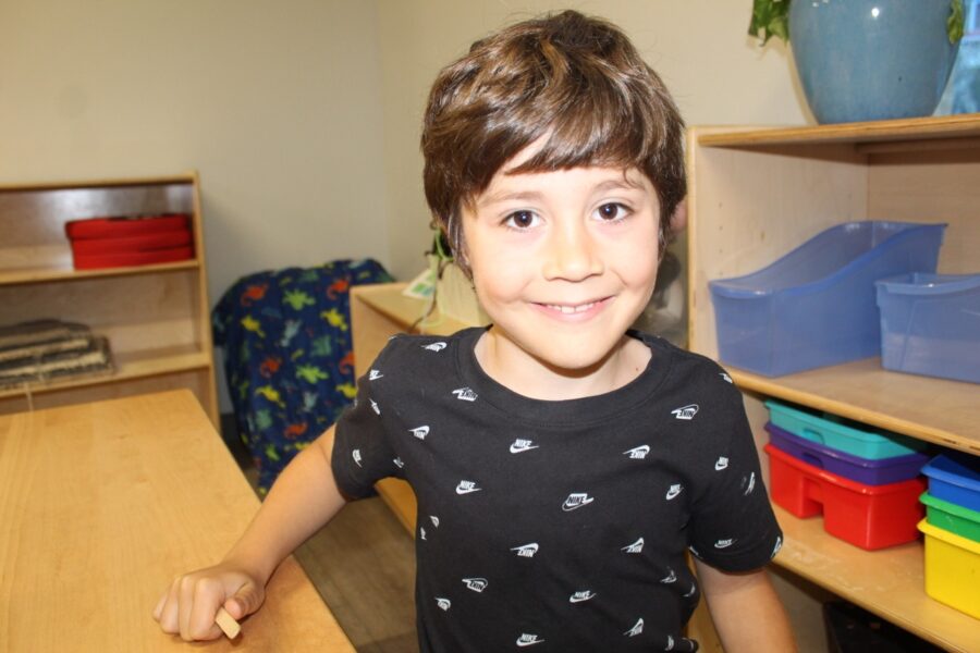 a young boy standing in front of a wooden table