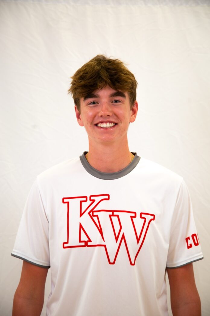 a young man wearing a white t - shirt with red letters on it