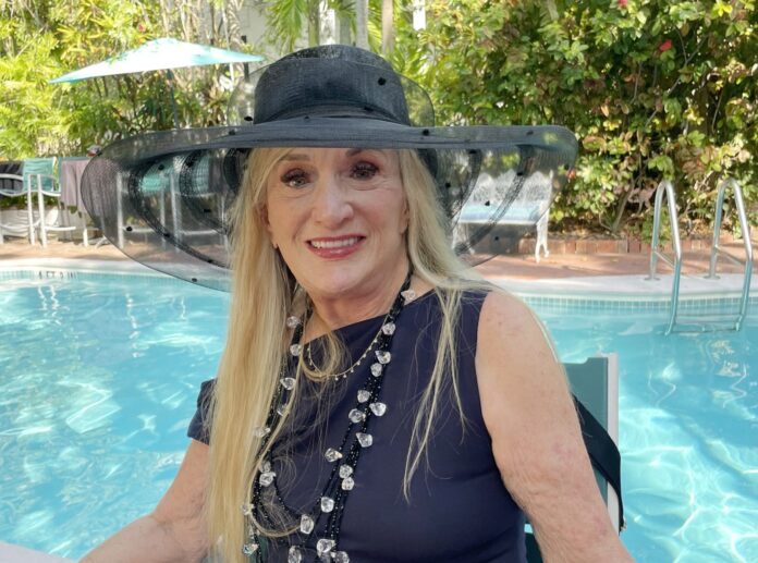 Kate Miano Derby Day best a woman sitting in a chair next to a pool wearing a hat