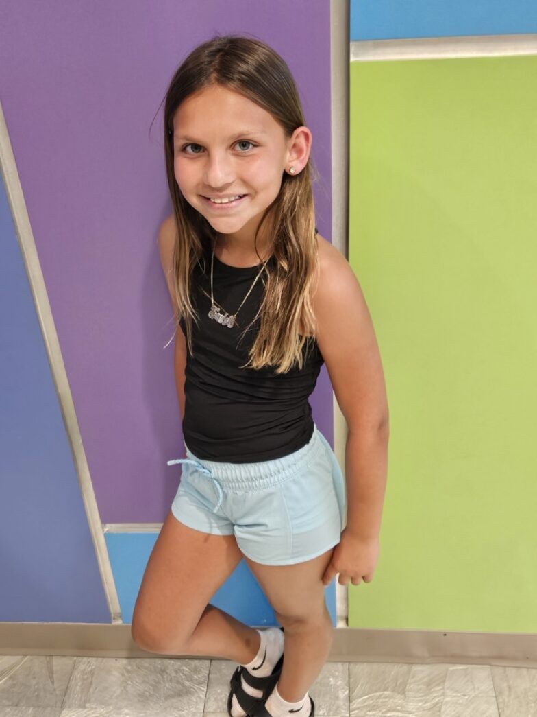 a little girl standing in front of a colorful wall
