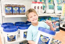 a young boy holding two buckets of food in a store