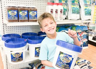 a young boy holding two buckets of food in a store