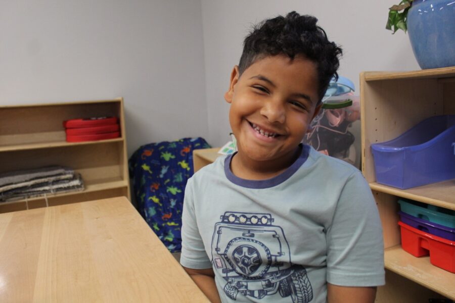 a young boy sitting at a desk in a classroom