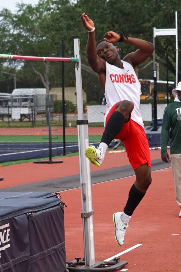 a man jumping over a pole on top of a track