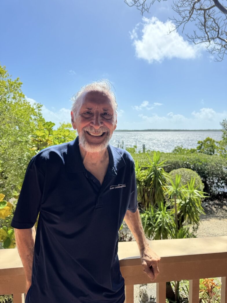 a man standing on a porch next to a tree
