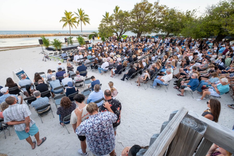 a crowd of people sitting on top of a sandy beach