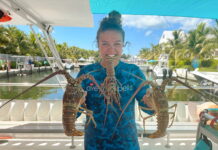 a woman holding a large lobster on a boat