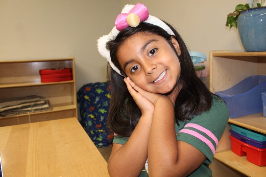 a young girl sitting at a desk with a laptop computer