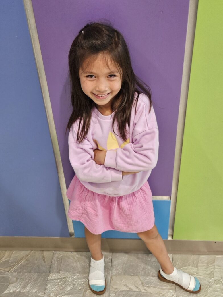 a little girl standing in front of a colorful wall