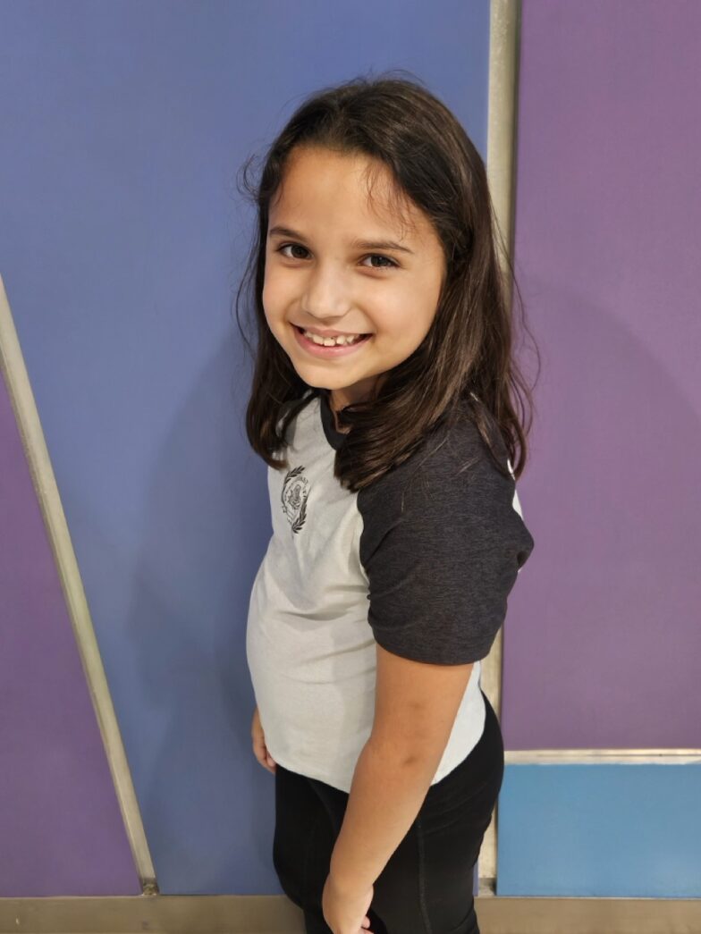 a little girl standing in front of a purple and blue wall