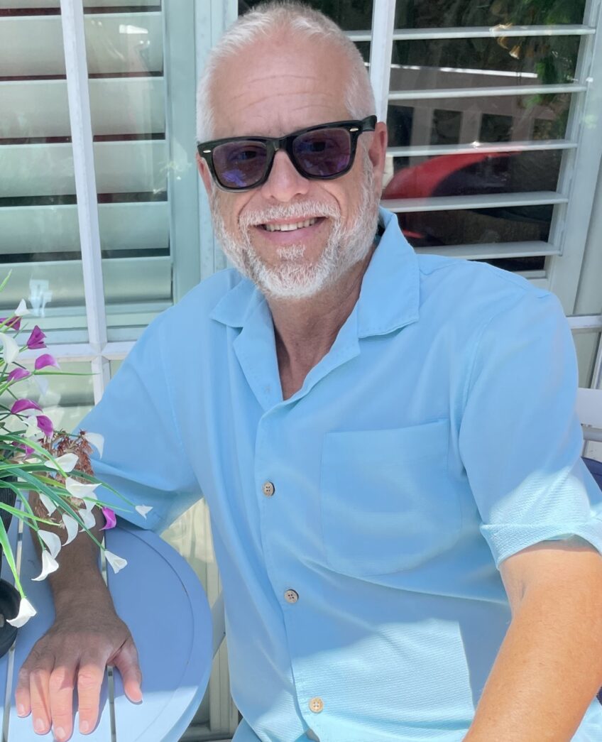 a man sitting at a table with a vase of flowers