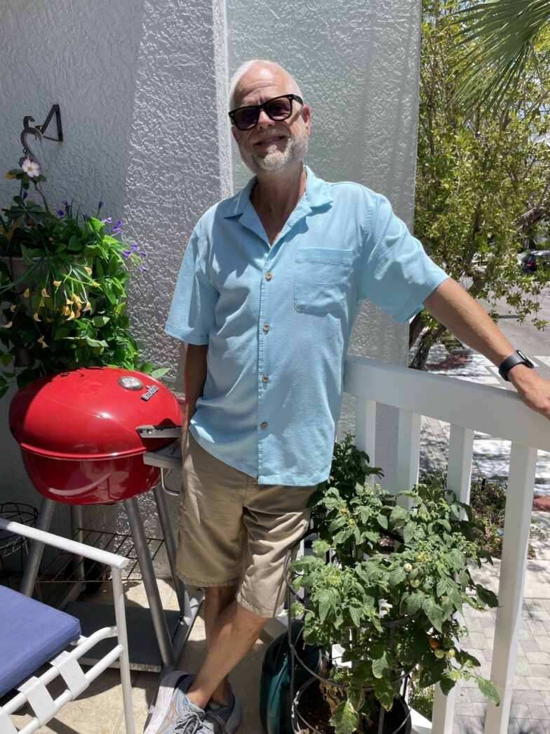 a man standing on a porch next to a grill
