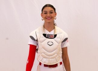 a woman wearing a catchers uniform and holding a baseball bat