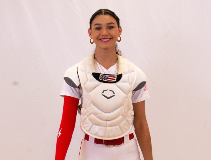 a woman wearing a catchers uniform and holding a baseball bat