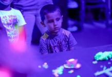 a young boy sitting at a table in front of a group of people