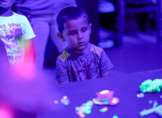 a young boy sitting at a table in front of a group of people