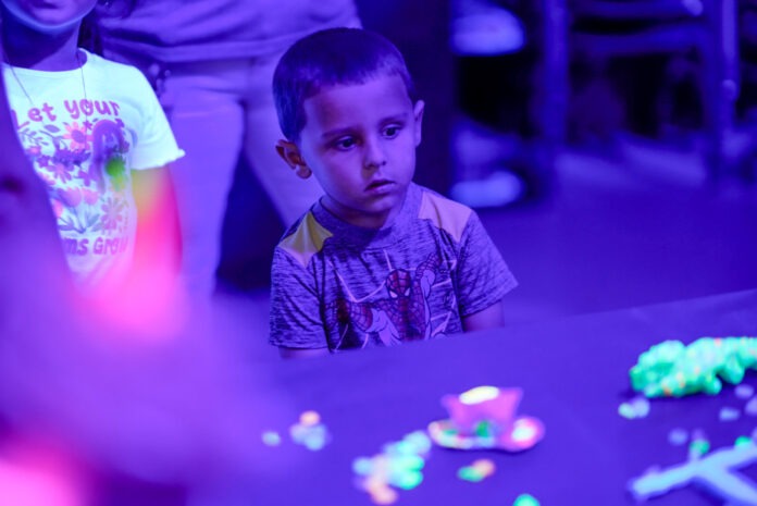 a young boy sitting at a table in front of a group of people