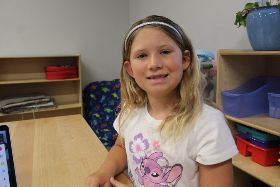a little girl sitting at a table with a laptop
