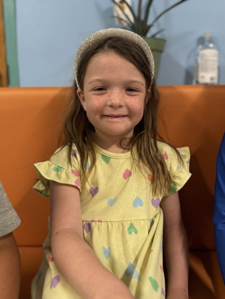 a little girl sitting on a couch with a cake in her hand