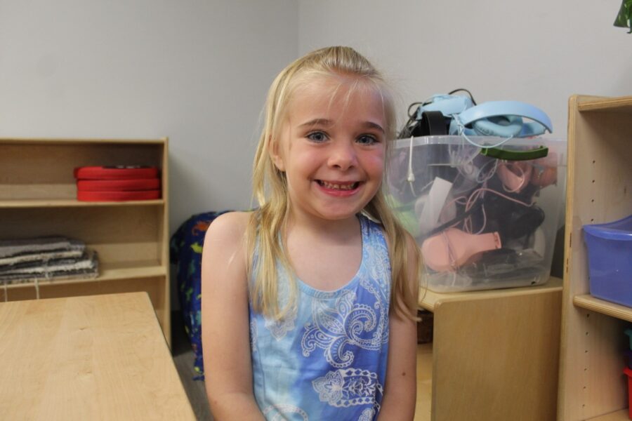 a little girl standing in front of a wooden desk