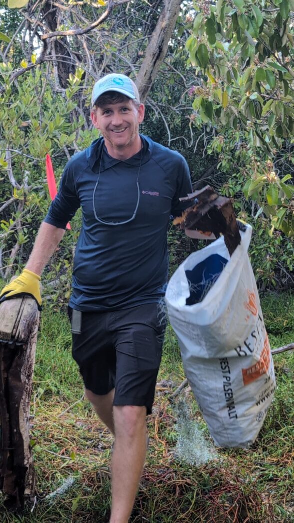 a man carrying a large bag of trash through a forest