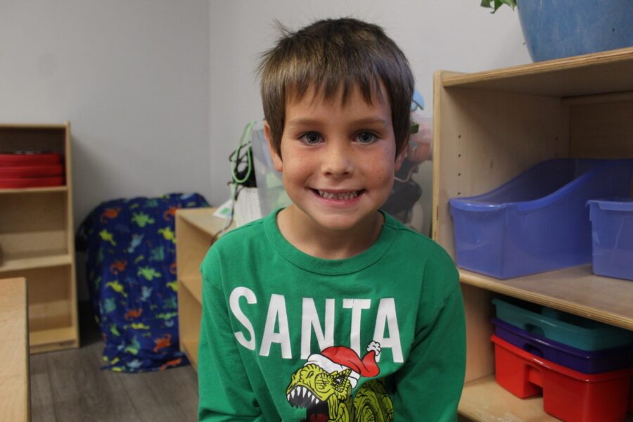 a young boy in a green shirt standing in a room