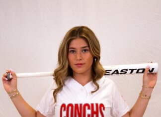 a woman in a baseball uniform holding a bat