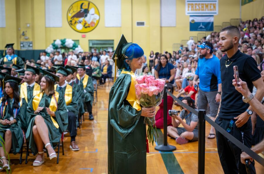 a woman in a graduation gown holding a bouquet of flowers