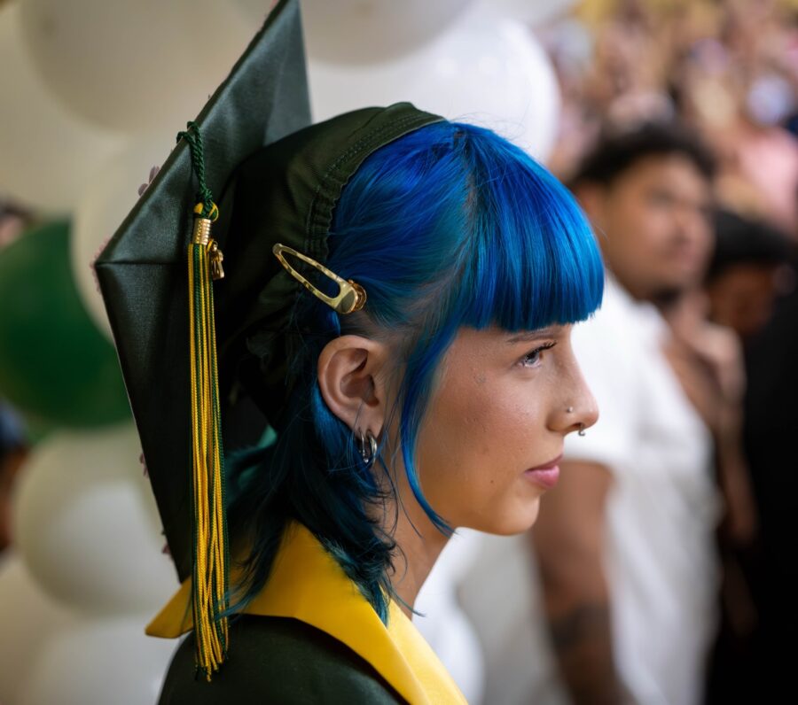 a woman with blue hair wearing a graduation cap and gown